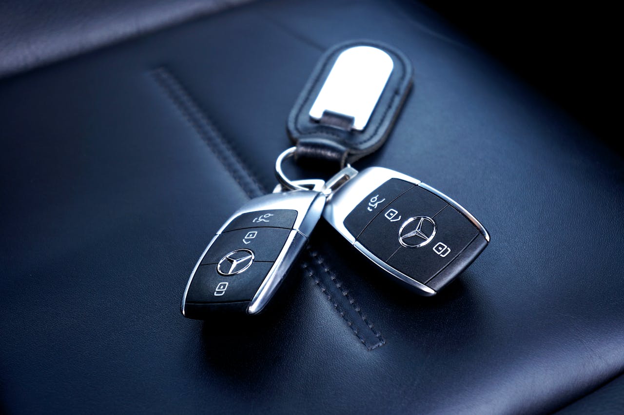 our-experience Two Mercedes Benz car keys resting on a luxurious leather seat, showcasing elegance and design.