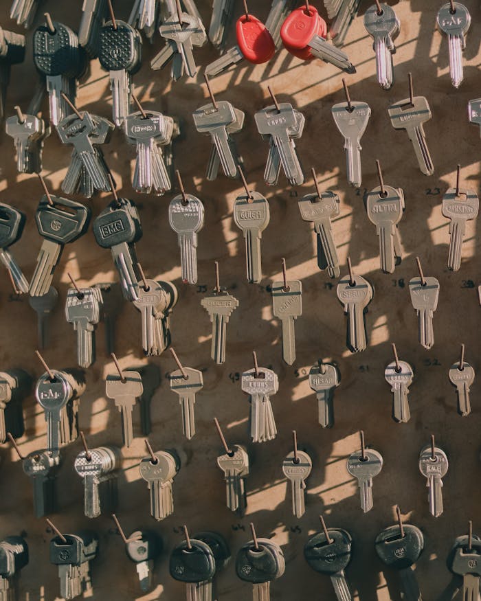 ours-journey A collection of assorted metal keys hanging on a wall with hooks, casting shadows.