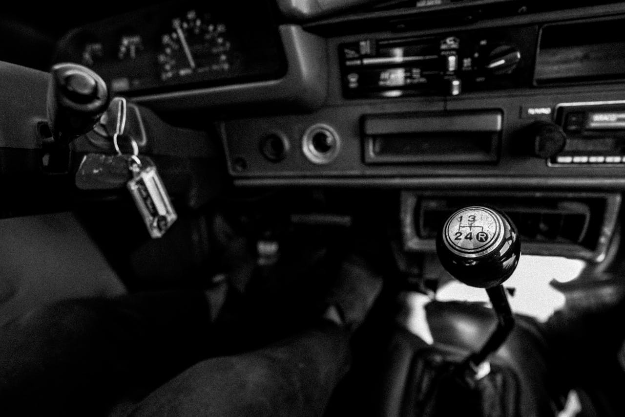 about-02 Black and white photo showcasing a vintage car interior with a manual gearshift and dashboard.